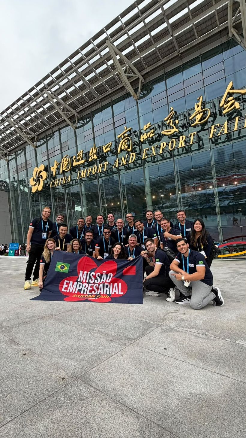 Grupo da missão empresarial da PBF Comex com a bandeira Missão Empresarial Canton Fair na entrada do centro de exposições China Import and Export Fair, em Guangzhou